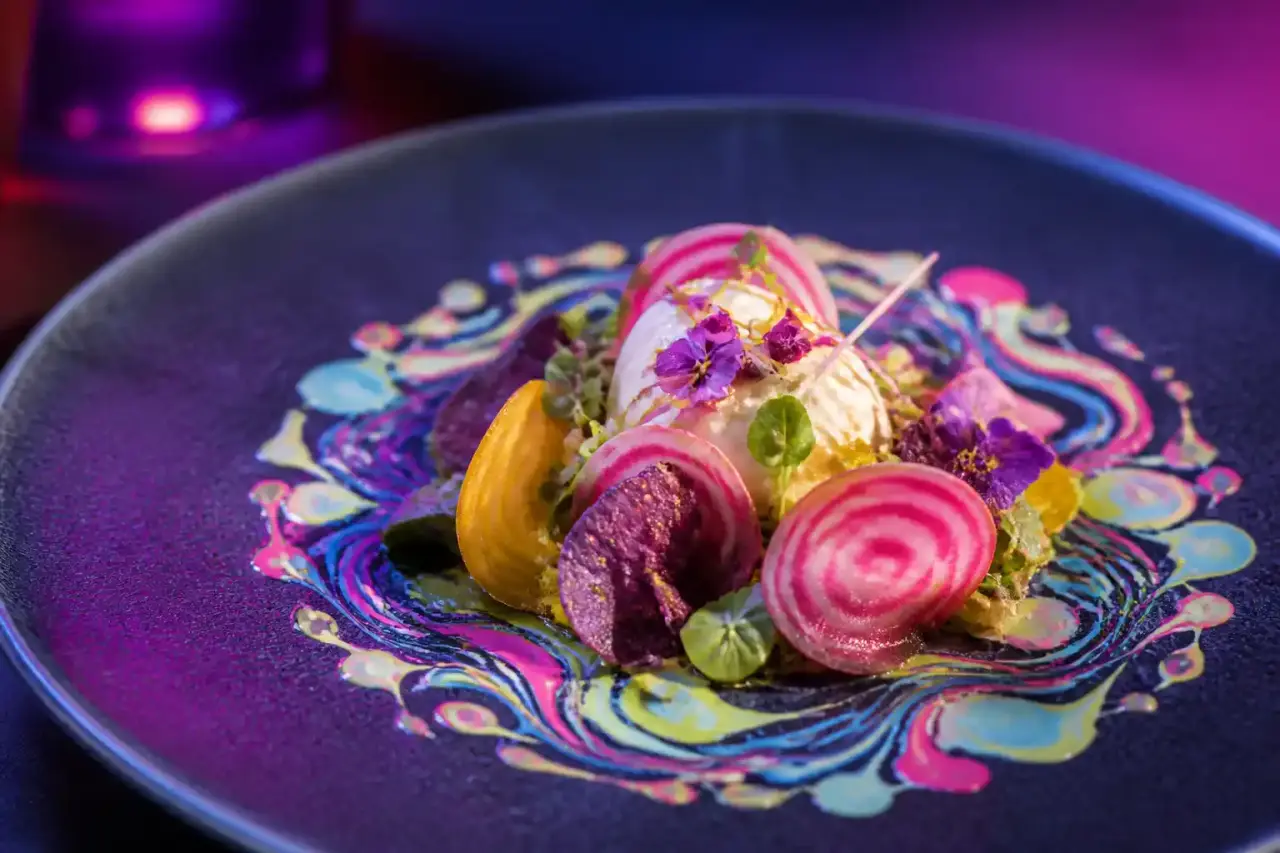 Assiette gastronomique psychédélique aux couleurs néon sur fond sombre